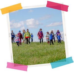 Children walk over a hill through a grass