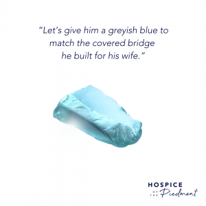 A piece of greyish blue sea glass with the quote, “Let’s give him a greyish blue to match the covered bridge he built for his wife.”