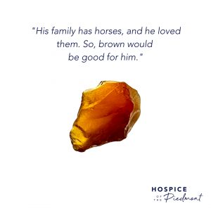 A piece of brown sea glass with the quote, "His family has horses, and he loved them. So, brown would be good for him."